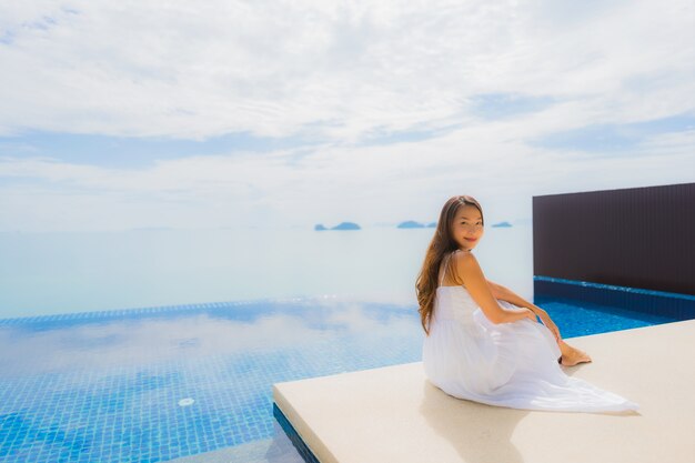 Женщина портрета молодая азиатская ослабляет улыбку счастливую вокруг бассейна в гостинице и курорте
