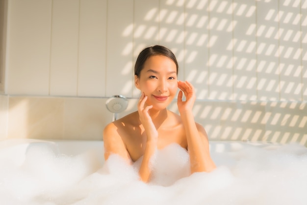 Женщина портрета молодая азиатская ослабляет принимает ванну в ванне