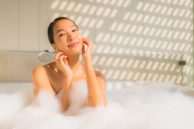 La giovane donna asiatica del ritratto si rilassa prende un bagno in vasca