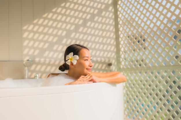 Женщина портрета молодая азиатская ослабляет принимает ванну в ванне