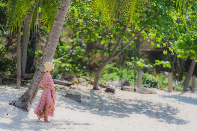 Улыбка женщины портрета молодая азиатская счастливая вокруг океана моря пляжа с пальмой кокоса на каникулы праздника