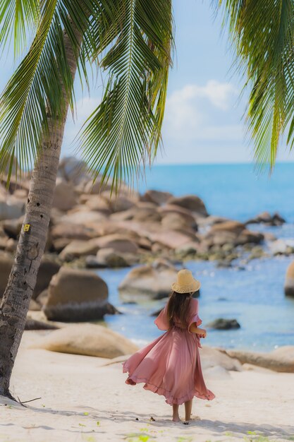 Free photo portrait young asian woman smile happy around beach sea ocean with coconut palm tree for holiday vacation