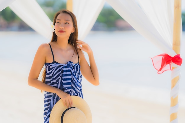 Free photo portrait young asian woman smile happy around beach sea ocean with coconut palm tree for holiday vacation