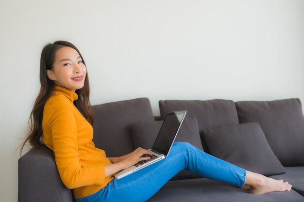 소파에 랩톱 컴퓨터 참고도 서를 사용 하여 세로 젊은 아시아 여자