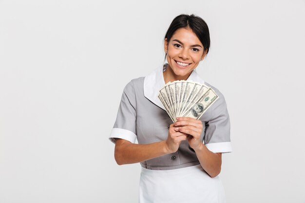 Portrait of young attractive female maid holding bunch of money