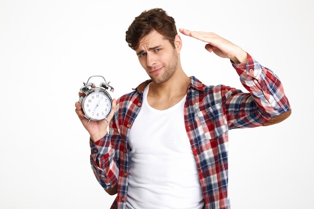 Portrait of a young attractive man holding alarm clock