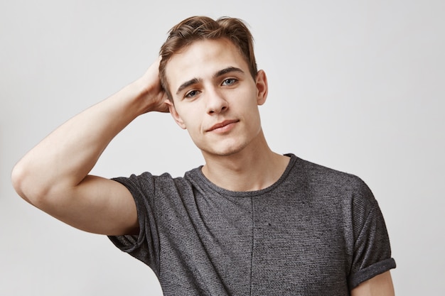 Portrait of young attractive man touching his hair. How do you like my new haircut.