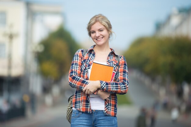 Portrait of young attractive student girl against blurred city street