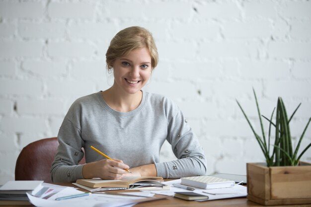 Portrait of a young attractive student at the table