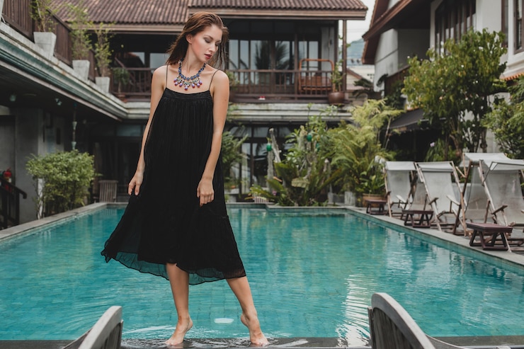 Free Photo portrait of young attractive woman in elegant dress, straw hat, summer style, fashion trend, vacation, smiling, stylish accessories, sunglasses, posing on tropical villa on bali