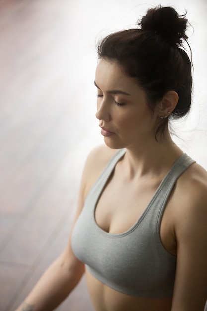 Portrait of young attractive woman meditating in yoga pose