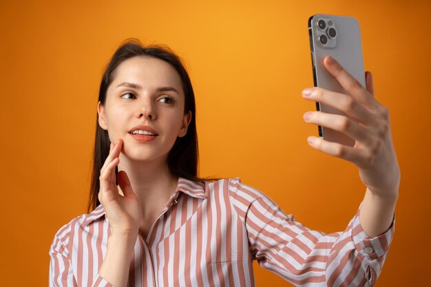 Portrait of young attractive woman using her smartphone against yellow background