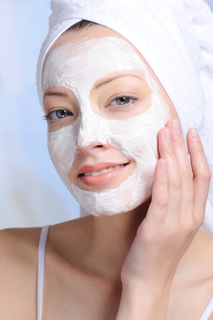 Portrait of young attractive woman with cosmetic mask on her face