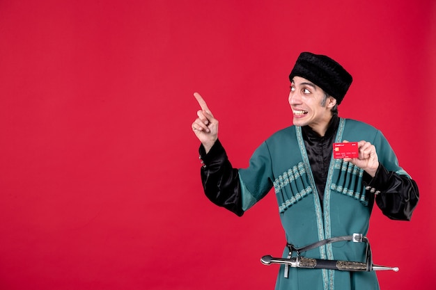 Portrait of young azeri man in traditional costume holding credit card on red