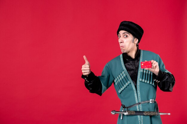 Portrait of young azeri man in traditional costume holding credit card on red