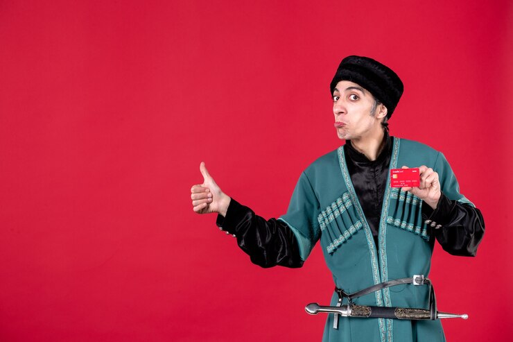 Free Photo portrait of young azeri man in traditional costume holding credit card on red