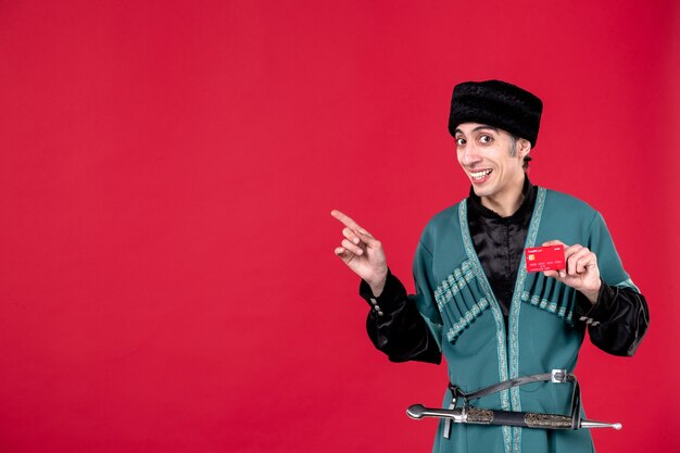 Portrait of young azeri man in traditional costume holding credit card on red