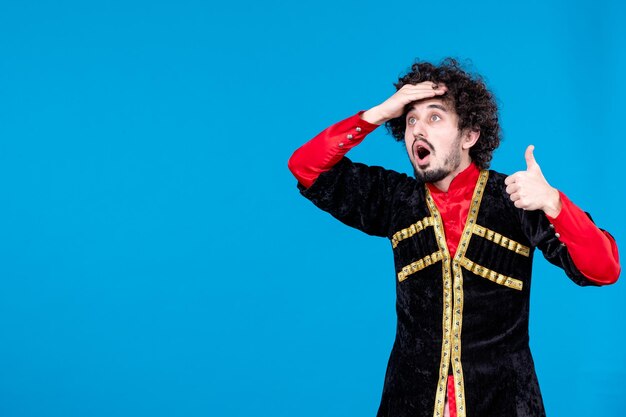 Portrait of young azeri man in traditional costume studio shot blue background ethnic novruz dancer spring colors