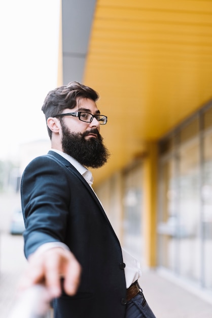 Portrait of young beard businessman with black eyeglasses looking away