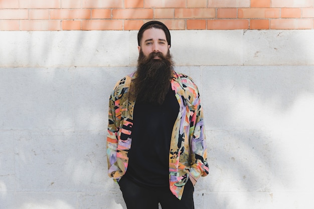 Free photo portrait of a young bearded man standing against white wall