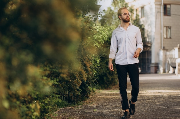 Free photo portrait of young bearded man wearing spectacles and walking in park