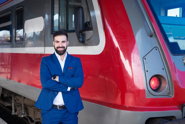 現代の地下鉄の電車の前に誇らしげに立っている青い制服を着た若いひげを生やした列車の運転手の肖像画