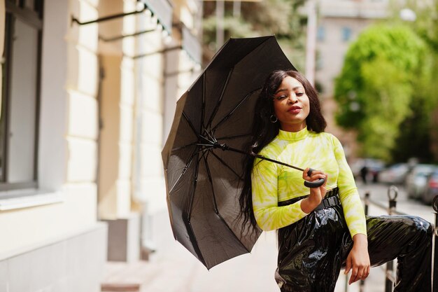 Portrait of young beautiful african american woman holding black umbrella