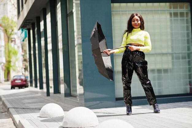 Portrait of young beautiful african american woman holding black umbrella