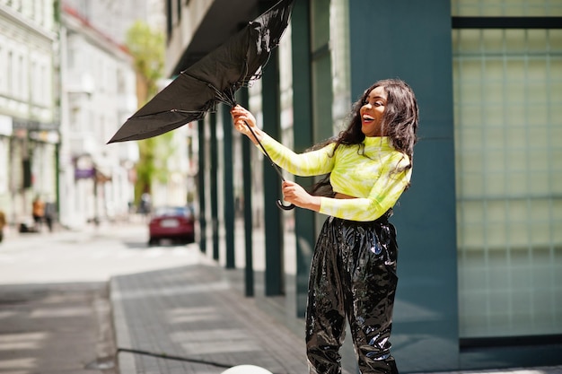 Portrait of young beautiful african american woman holding black umbrella