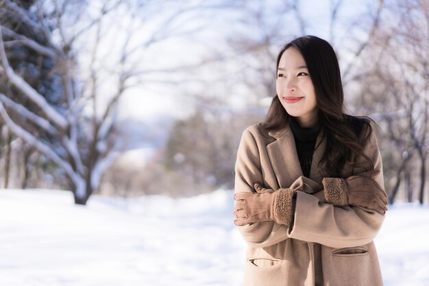 肖像画若い美しいアジアの女性は幸せな旅行を笑顔し、雪の冬の季節を楽しみ