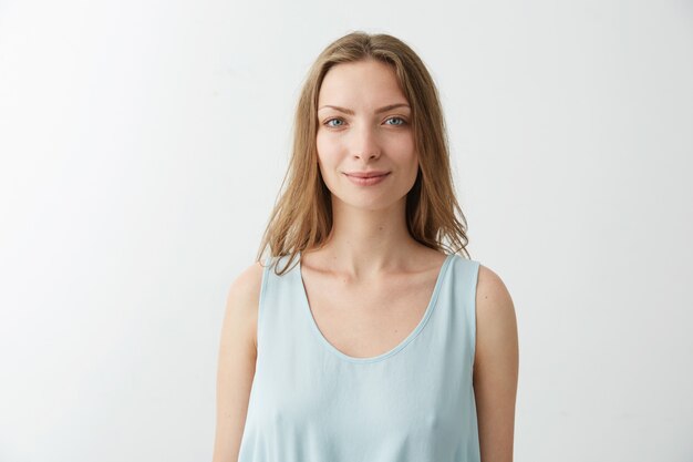 Portrait of young beautiful blonde girl with blue eyes smiling .