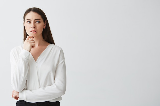 Portrait of young beautiful brunette businesswoman dreaming thinking frowning . Hand on chin.