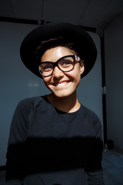 Portrait of young beautiful brunette girl in black hat smiling.