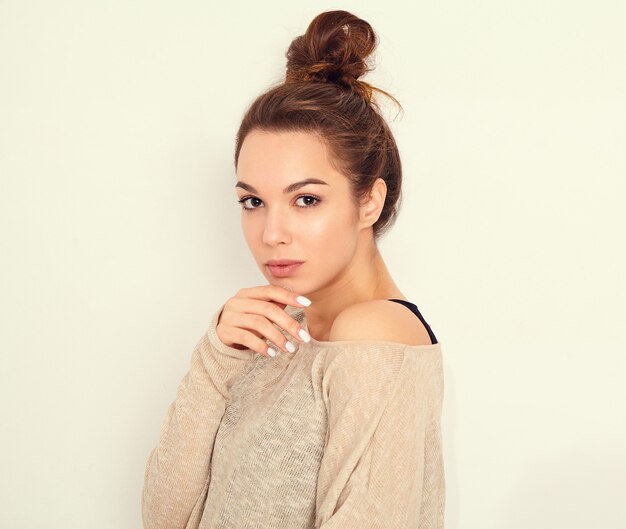 Portrait of young beautiful brunette woman girl model with nude makeup in summer clothes posing near wall. 