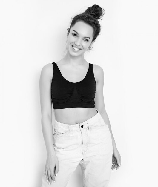 Portrait of young beautiful brunette woman girl model with nude makeup in summer T-shirt top and jeans clothes posing near wall. 