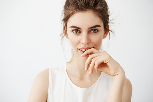 Portrait of young beautiful brunette woman posing touching face over white background.