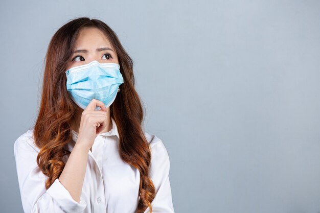 Free photo portrait of young beautiful business woman wearing face mask on gray surface