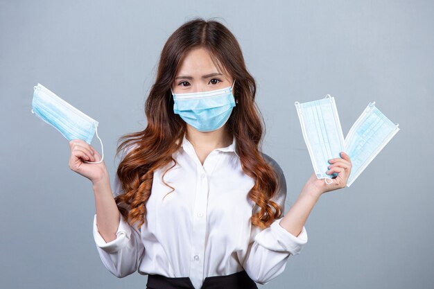 Portrait of young beautiful business woman wearing face mask on gray surface