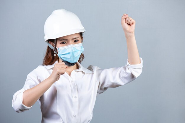 Portrait of young beautiful business woman wearing face mask on gray surface