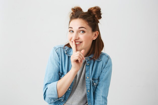 Portrait of young Beautiful cute girl with two buns smiling showing to keep silence .