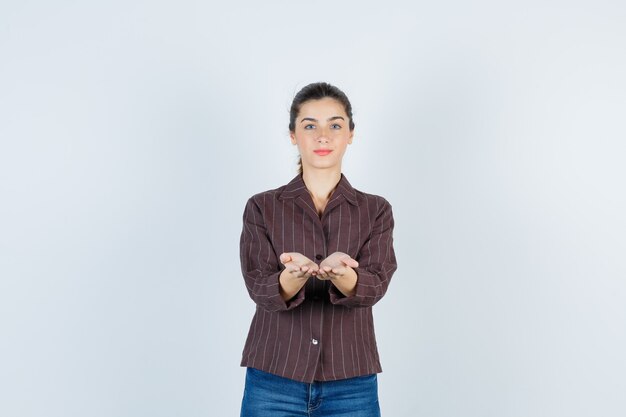 Portrait of young beautiful female pretending to hold something in jacket and looking confident front view