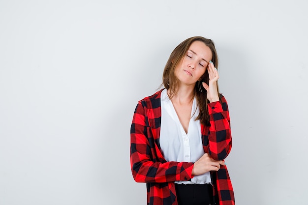 Portrait of young beautiful female suffering from headache in casual outfit and looking painful front view