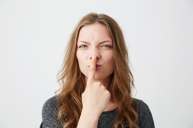 Free photo portrait of young beautiful girl making funny face touching her nose .