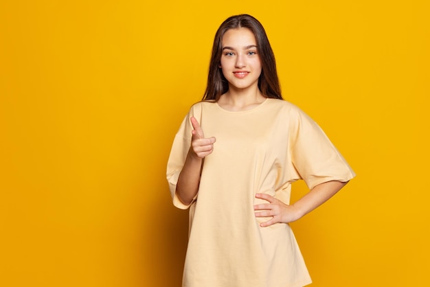 Portrait of young beautiful girl posing isolated over yellow studio background