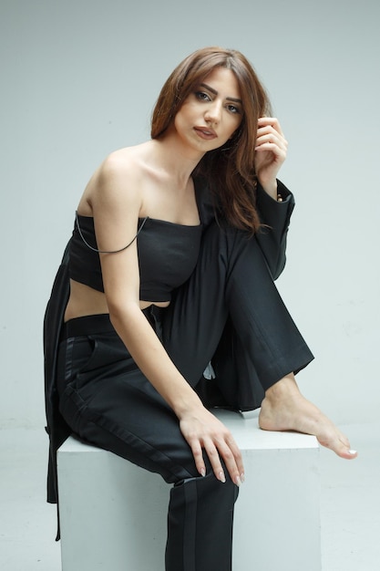 Portrait of a young beautiful girl sitting on white box and stretching her hair High quality photo