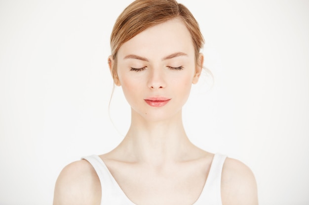 Portrait of young beautiful girl with clean fresh skin isolated on white background. Closed eyes. Beauty and health lifestyle.