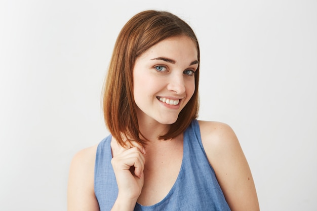 Portrait of young beautiful happy girl with natural make up smiling touching hair .