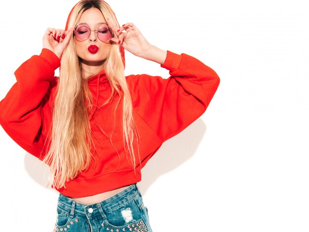 Portrait of young beautiful hipster bad girl in trendy red  hoodie and earring in her nose.  Positive model having fun.Isolated on white