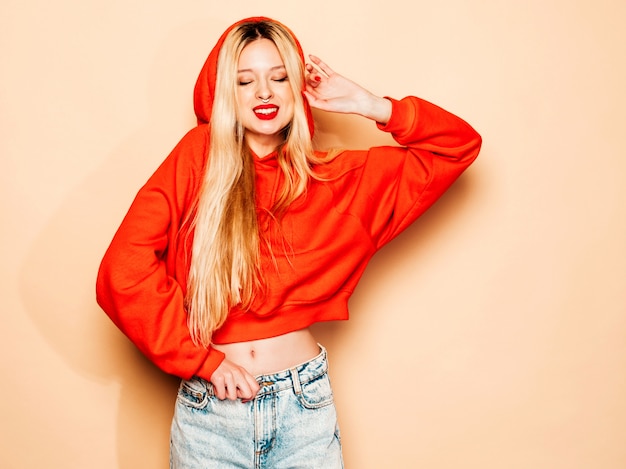 Portrait of young beautiful hipster bad girl in trendy red  hoodie and earring in her nose.  Positive model having fun