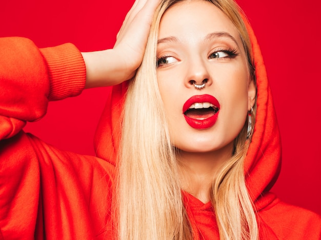 Portrait of young beautiful hipster bad girl in trendy red  hoodie and earring in her nose.  positive model having fun